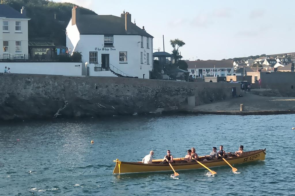 Gig rowers pass the Ship Inn in Porthleven 